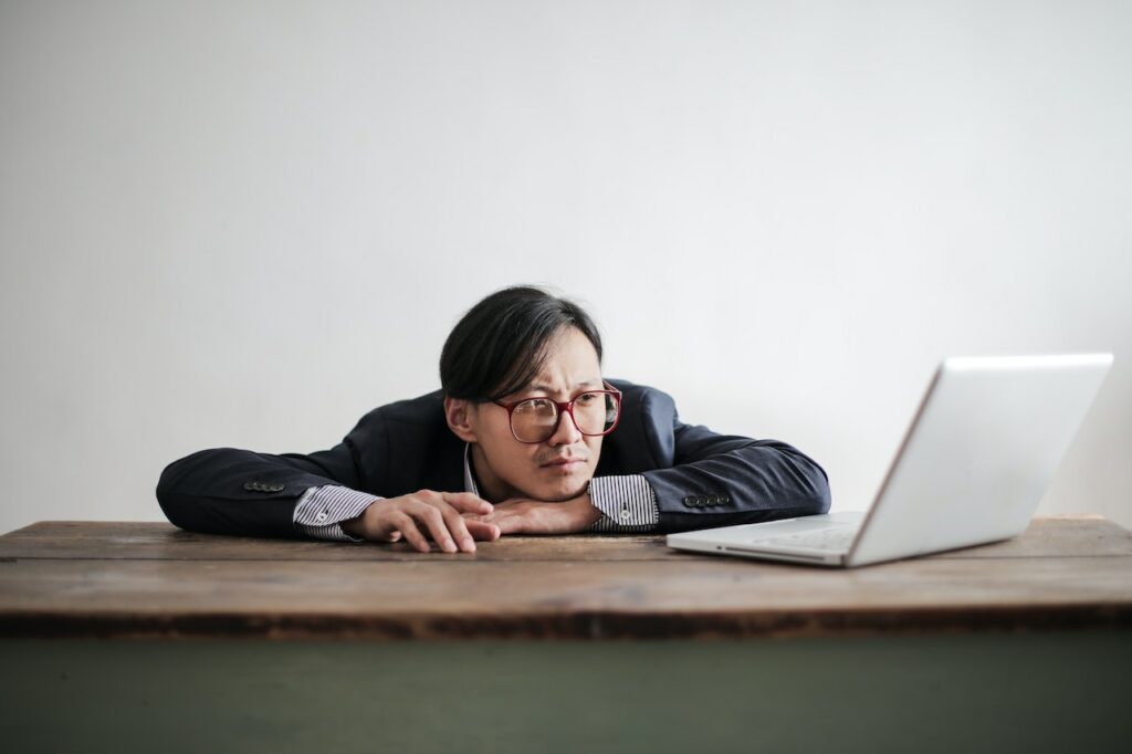 A man laying on the table and watching at the computer